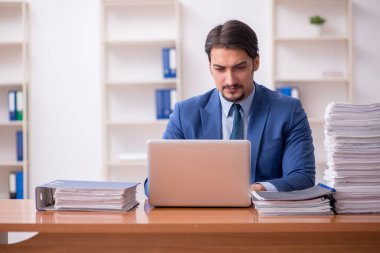 Genç bir erkek çalışan ve ofiste çok fazla iş var.