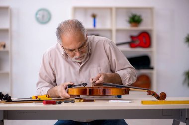 Eski tamirci atölyede müzik aletlerini tamir ediyor.
