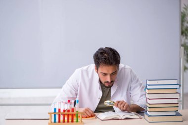 Genç kimyacı öğretmen beyaz tahtanın önünde.