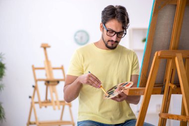 Genç erkek ressam evde resim yapmaktan hoşlanıyor.