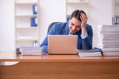 Genç bir erkek çalışan ve ofiste çok fazla iş var.