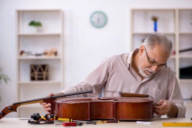 Eski tamirci atölyede müzik aletlerini tamir ediyor.