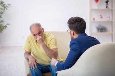 Yaşlı adam genç psikoterapisti ziyaret ediyor.