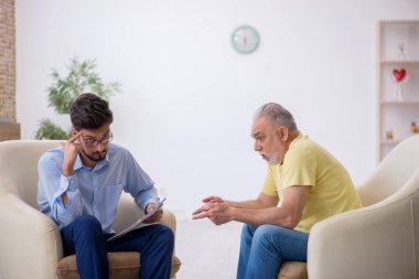 Yaşlı adam genç psikoterapisti ziyaret ediyor.