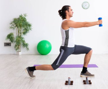 Genç yakışıklı adam içeride spor egzersizleri yapıyor.