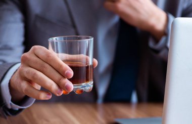 Erkek çalışan işyerinde alkol içiyor ve sigara içiyor.