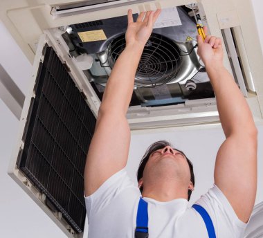 The worker repairing ceiling air conditioning unit clipart