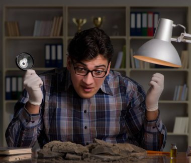 Arkeolog gece geç saatlere kadar ofiste çalışıyor.