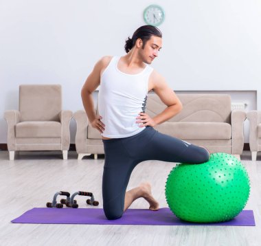 Genç adam evde antrenman ve egzersiz yapıyor.