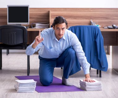 Genç yakışıklı işadamı iş yerinde egzersiz yapıyor.