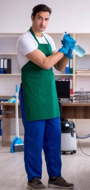 Genç yakışıklı müteahhit ofisi temizliyor.