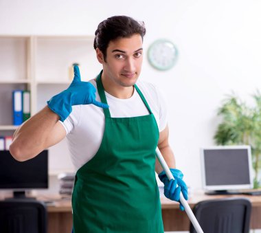Genç yakışıklı müteahhit ofisi temizliyor.