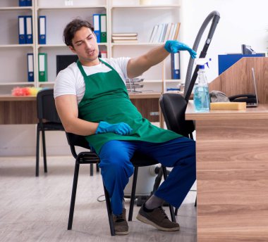 Genç yakışıklı müteahhit ofisi temizliyor.