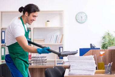 Genç yakışıklı müteahhit ofisi temizliyor.