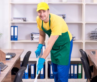 Genç erkek müteahhit ofisi temizliyor.