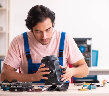 Genç erkek müteahhit bilgisayarı tamir ediyor.