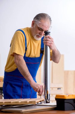 Atölyede çalışan yaşlı erkek marangoz.