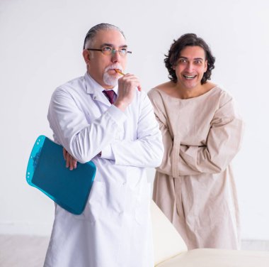 Genç hastayı muayene eden yaşlı erkek psikiyatrist.