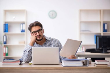 Genç erkek çalışan işyerinde oturuyor.