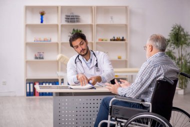 Tekerlekli sandalyedeki yaşlı hasta genç erkek doktoru ziyaret ediyor.