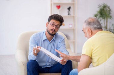 Yaşlı adam genç psikoterapisti ziyaret ediyor.