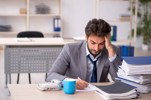 Молодой бизнесмен и слишком много работы в офисе