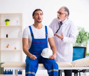 Genç erkek müteahhit yaşlı doktoru ziyaret ediyor.