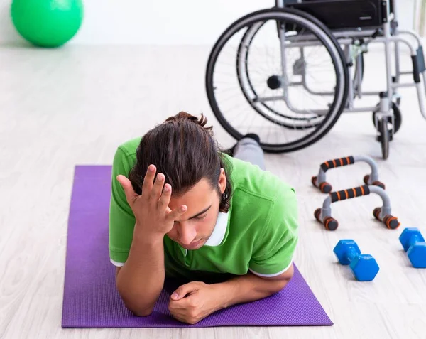 The young man in wheel-chair doing exercises indoors