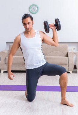 Genç adam evde antrenman ve egzersiz yapıyor.