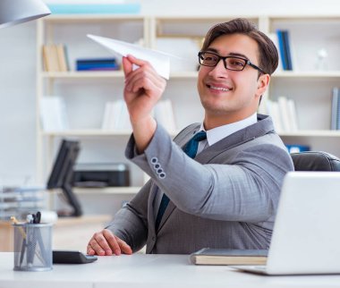 Ofisinde kağıt uçağı olan bir işadamı.