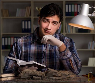Arkeolog gece geç saatlere kadar ofiste çalışıyor.