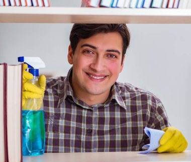 Kitap rafından toz temizleyen adam.