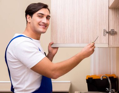 Genç adam mutfak mobilyalarını monte ediyor.