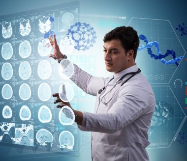 Erkek doktor MRI taramasının röntgenini çekiyor.