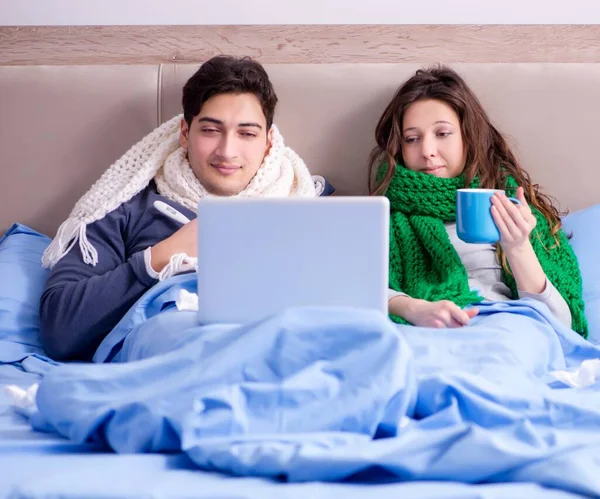 The sick wife and husband in bed with laptop
