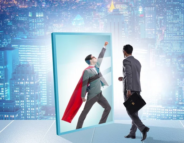 The businessman seeing himself in mirror as superhero