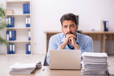 Genç işadamı ve işyerinde çok fazla iş var.