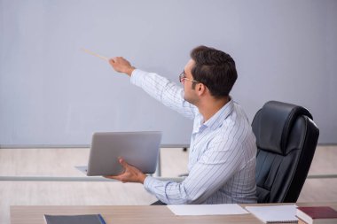 Genç erkek öğretmen beyaz tahtanın önünde.