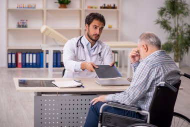 Tekerlekli sandalyedeki yaşlı hasta genç erkek doktoru ziyaret ediyor.