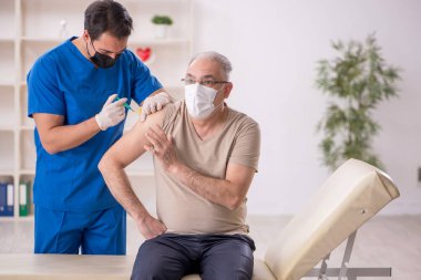 Yaşlı hasta aşılama konseptinde genç erkek doktoru ziyaret ediyor.