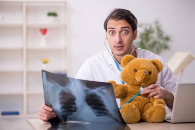 Young doctor holding toy bear clipart
