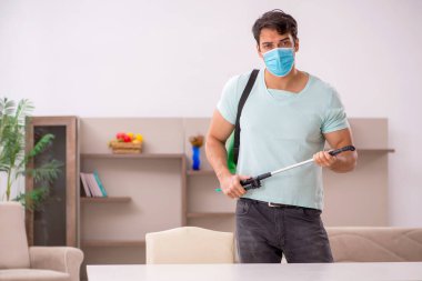 Genç müteahhit evde haşere kontrolü yapıyor.