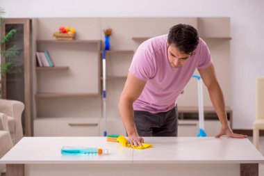 Genç müteahhit evi temizliyor.