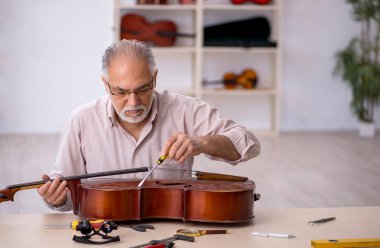 Eski tamirci atölyede müzik aletlerini tamir ediyor.