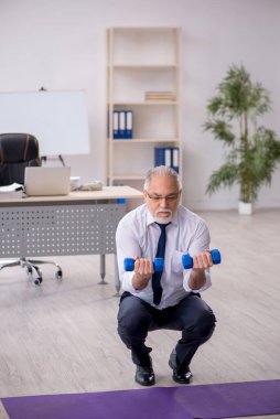 Eski erkek çalışanın teneffüste spor egzersizleri yapıyor.