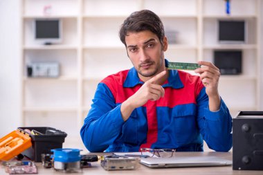 Atölyede bilgisayar tamir eden genç bir tamirci.