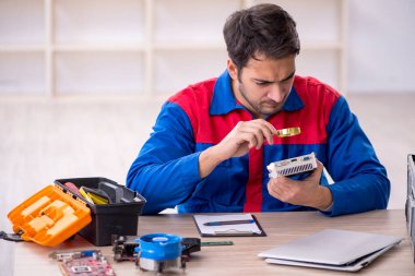 Atölyede bilgisayar tamir eden genç bir tamirci.