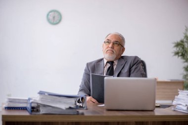 Eski erkek patron iş yerinde oturuyor.