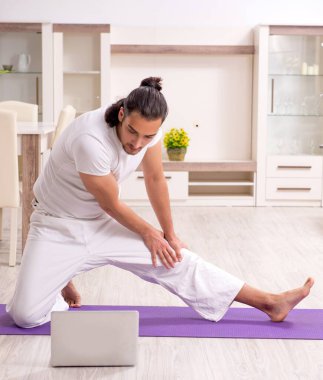 Genç adam evde fiziksel egzersiz yapıyor.