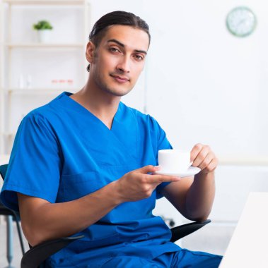 Klinikte çalışan genç erkek doktor.